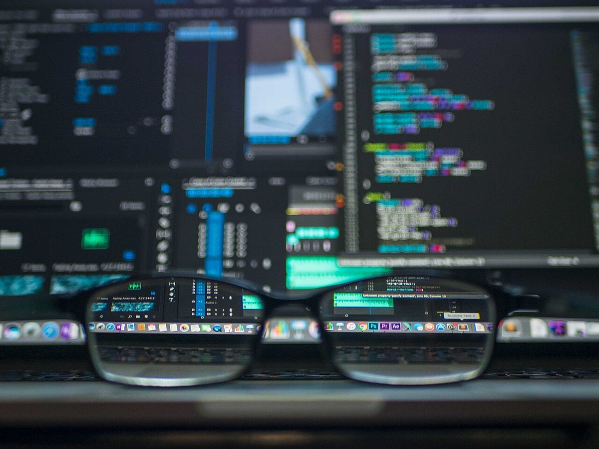 Brille liegt vor einem Bildschirm mit Programmcode