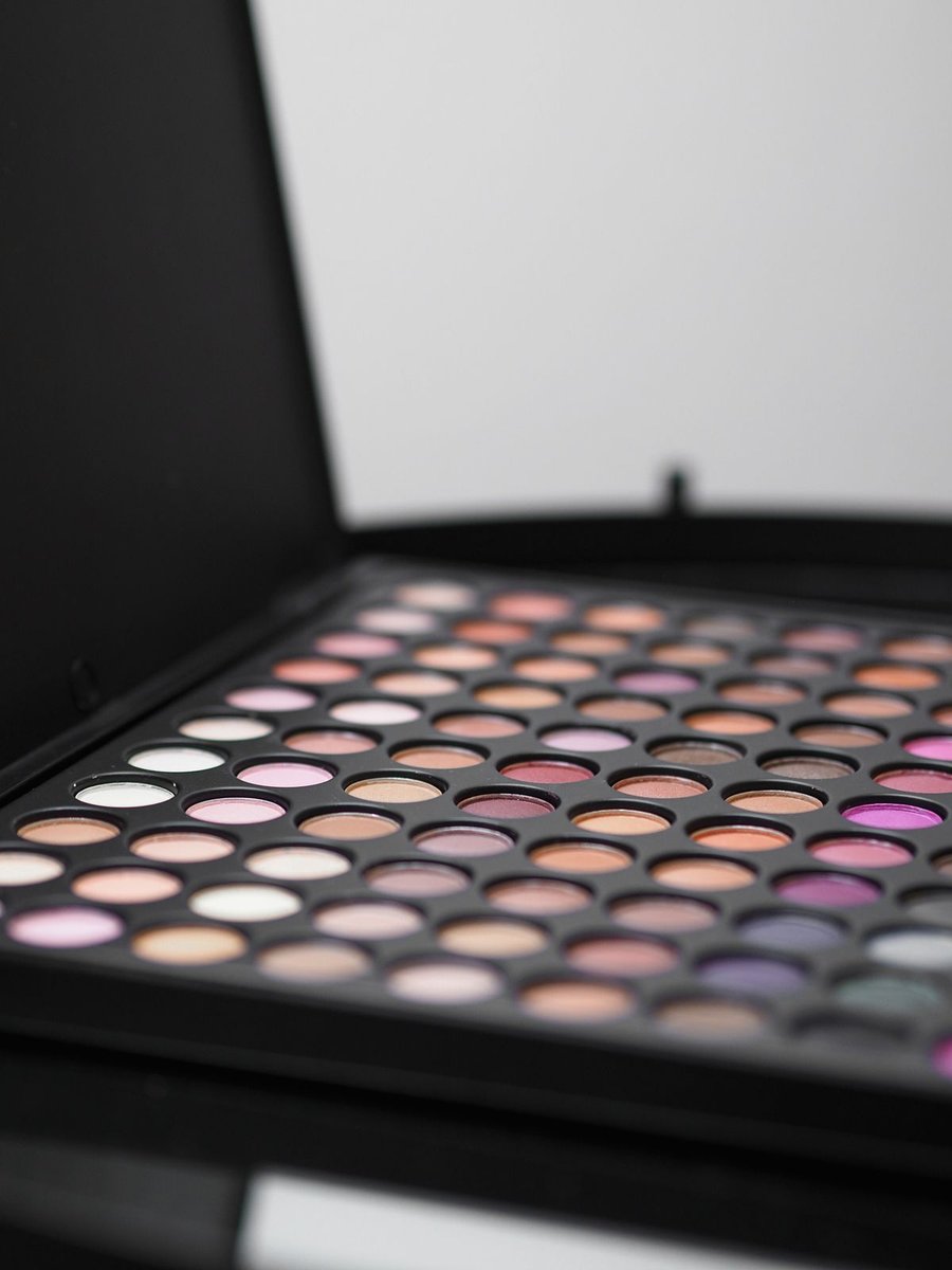 Geöffnete Lidschattenpalette mit vielen runden Farbpfännchen in Rosé, Violett und Beige