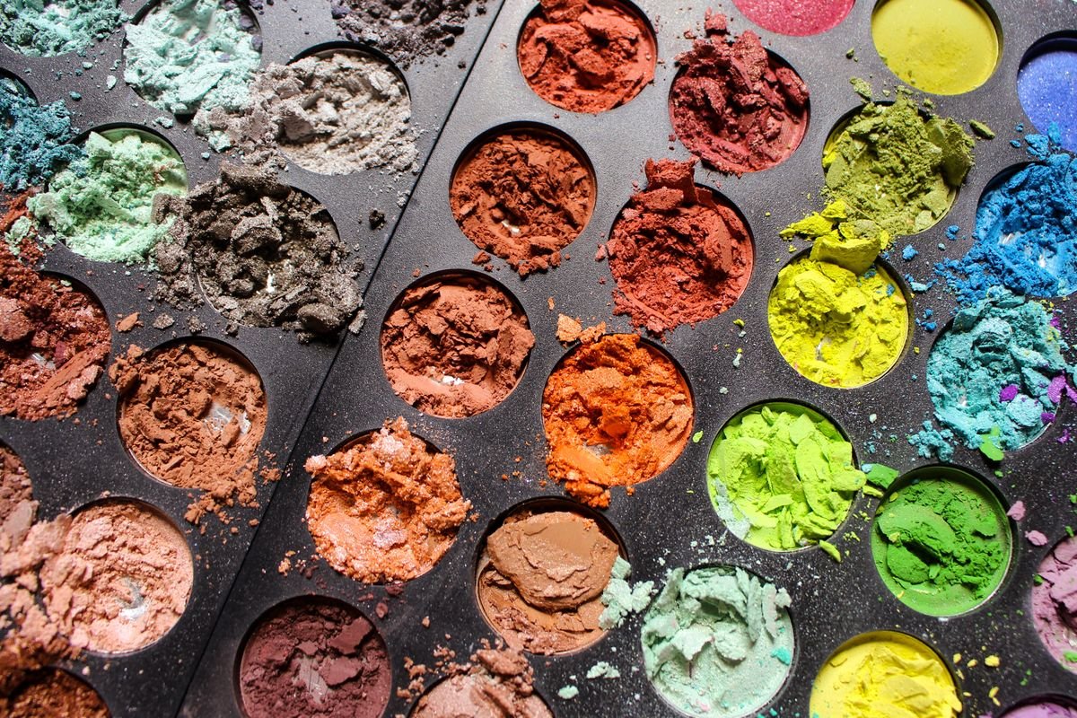 Aufgebrochene, bunte Lidschattenpfännchen in einer schwarzen Palette von oben